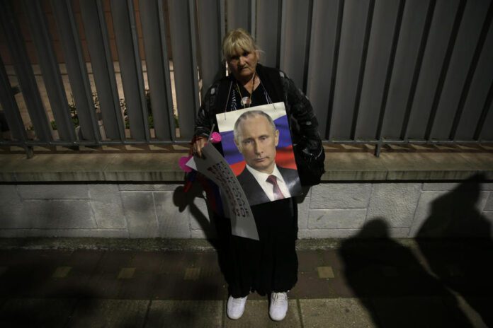 Moteris laiko Rusijos prezidento Vladimiro Putino nuotrauką per prorusišką protestą Belgrade (Serbija) / EPA nuotr.