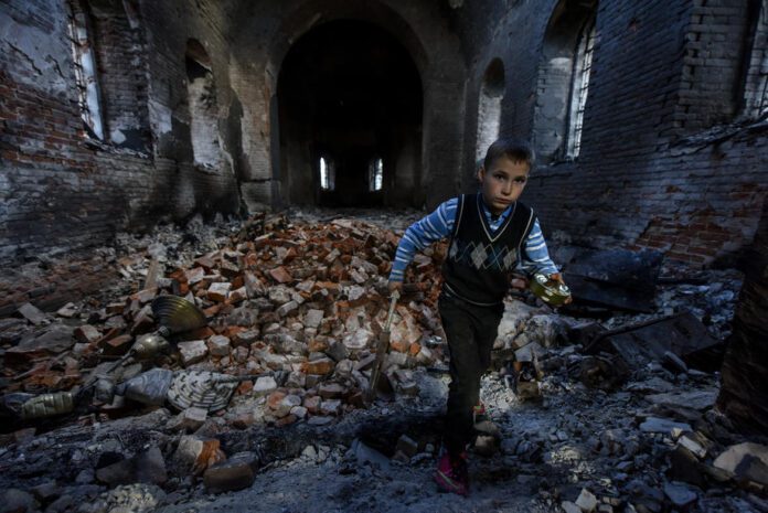 Berniukas tarp griuvėsių Ukrainoje / EPA nuotr.