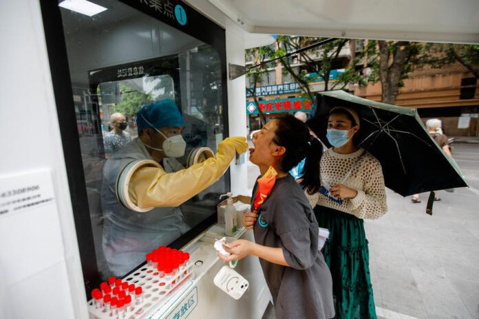 Medicinos darbuotojas paima mėginį iš moters Čongčinge (Kinija) / EPA nuotr.