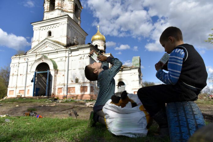 Vaikai prie apgriautos bažnyčios Lukašivkos kaime, Ukrainoje / EPA nuotr.