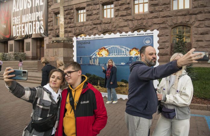 Ukrainiečiai fotografuojasi ir pozuoja priešais menininkų kolektyvo sukurtą pašto ženklą Kijevo centre, Ukrainoje / EPA nuotr.