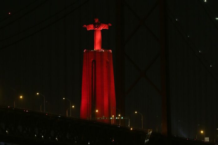 Raudona šviesa apšviesta Kristaus Karaliaus statula Portugalijoje / EPA nuotr.
