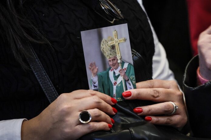 Tikinčioji su paveikslėliu, kuriame pavaizduotas Benediktas XVI / EPA nuotr.