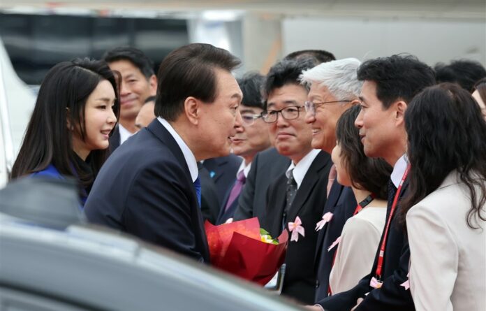 Pietų Korėjos prezidentas Yoonas Sukas Yeolas ir jo žmona Kim Keon Hee sveikinasi su pareigūnais, atvykusiais į Hirošimos oro uostą Hirošimoje, Japonijoje / EPA nuotr.