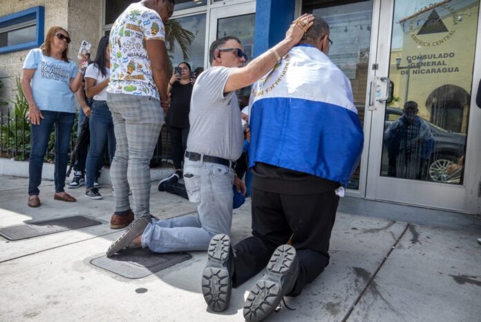 Katalikų kunigas Jose Palmaras (dešinėje) meldžiasi prie įėjimo į Nikaragvos konsulato būstinę Majamyje, Floridos valstijoje / EPA nuotr.