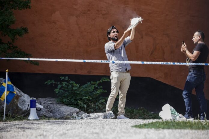 Irakietis Salwanas Momika padega Korano kopiją prie mečetės Stokholme (Švedija) / EPA nuotr.