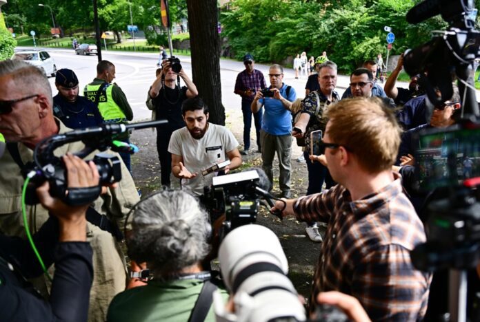 Asmuo (centre), kuriam policija leido viešai sudeginti Torą ir Bibliją prie ambasados, kalbasi su žiniasklaidos atstovais Stokholme (Švedija) / EPA nuotr.