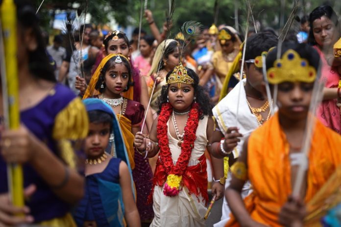 Vaikai, apsirengę hinduistų dievų Viešpaties Krišnos ir deivės Radhos kostiumais, dalyvauja eisenoje festivalio „Krišna Janmashtami