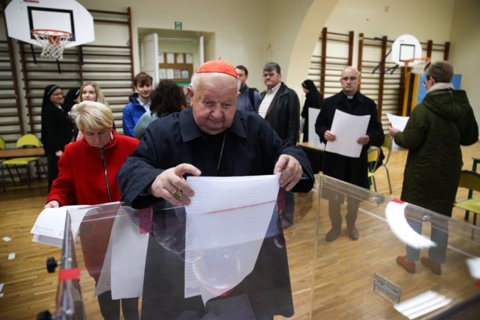 Krokuvos arkivyskupijos vyresnysis arkivyskupas kardinolas Stanislavas Dzivišas laiko balsavimo biuletenius prieš balsavimą rinkimų apylinkėje Krokuvoje, Lenkijoje / EPA nuotr.