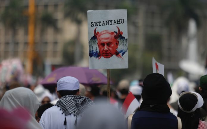 Indonezietis laiko ženklą su Izraelio ministro pirmininko Benjamino Netanyahu atvaizdu per palestiniečius palaikantį mitingą / EPA nuotr.