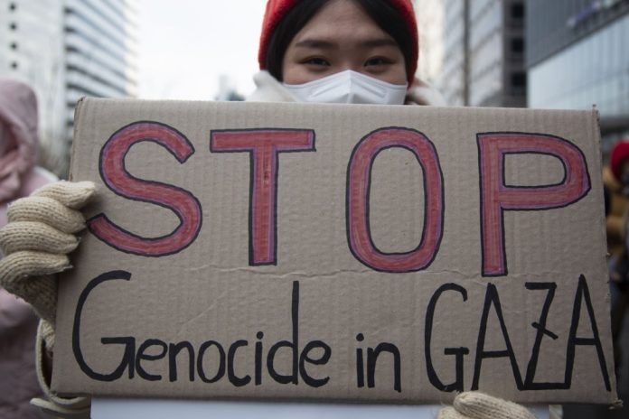 Protestuotojos plakatas „Sustabdykite genocidą Gazoje