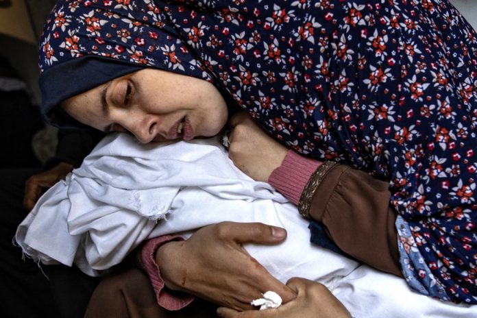 Sielvartaujanti motina dvynių mergaičių, priklausančių palestiniečių šeimai, žuvusių po Izraelio oro antskrydžio, per kurį žuvo 14 žmonių, Al-Nadžaro ligoninės Rafoje teritorijoje, Gazos Ruožo pietuose / EPA nuotr.