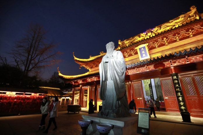 Lankytojai eina pro Konfucijaus statulą Nandzingo Konfucijaus šventykloje, esančioje ant Činghajaus upės kranto Nandzingo mieste, Dziangsu provincijoje, Kinijoje, 2017 m. gruodžio 12 d. / EPA nuotr.