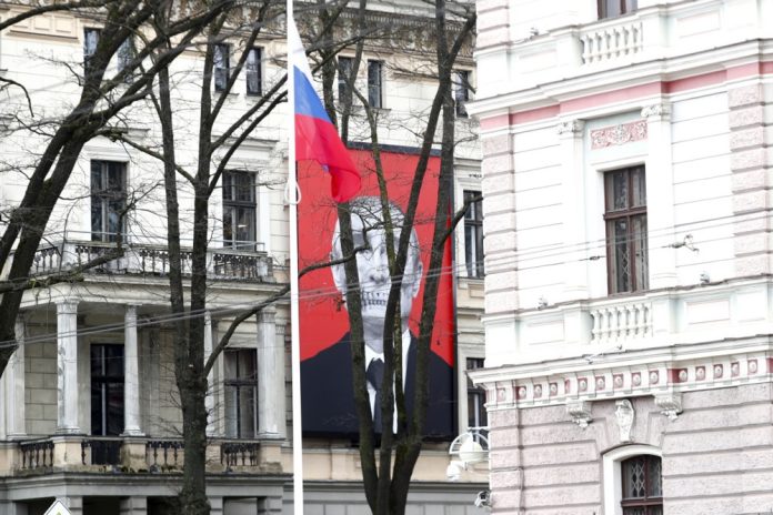 Stilizuotas Rusijos prezidento Vladimiro Putino „mirties galvos“ plakatas ant Medicinos istorijos muziejaus fasado priešais Rusijos ambasados pastatą, kai Latvijoje gyvenantys rusai laukia eilėje paskutinę balsavimo Rusijos prezidento rinkimuose dieną prie tos pačios ambasados Rygoje, Latvijoje, 2024 m. kovo 17 d.