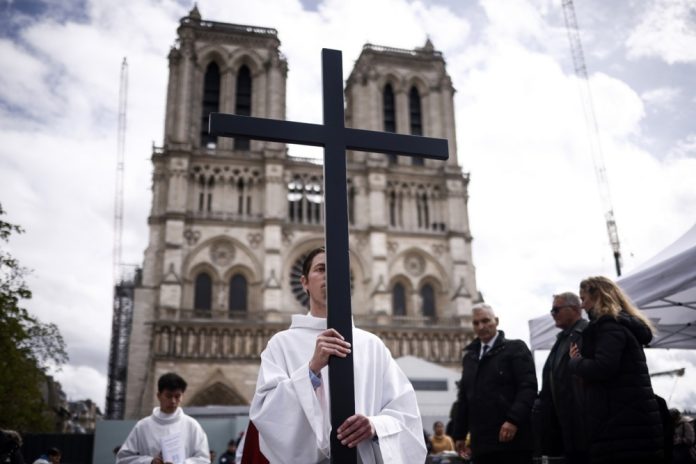 Kunigas eina su kryžiumi Didžiojo penktadienio procesijoje prie Notre Dame katedros Paryžiuje, Prancūzijoje, 2024 m. kovo 29 d.
