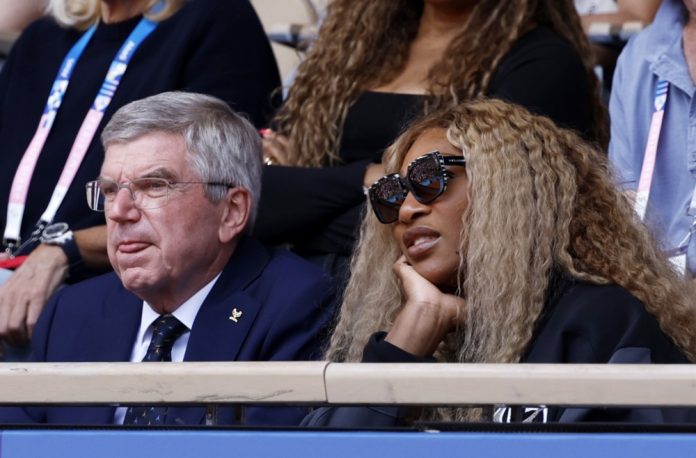 TOK prezidentas Thomas Bachas (kairėje) ir Serena Williams (dešinėje) stebi ispano Carloso Alcarazo ir serbo Novako Djokovičiaus žaidimą per 2024 m. Paryžiaus olimpinių žaidynių teniso varžybų vyrų vienetų varžybų aukso medalio mačą „Roland Garros